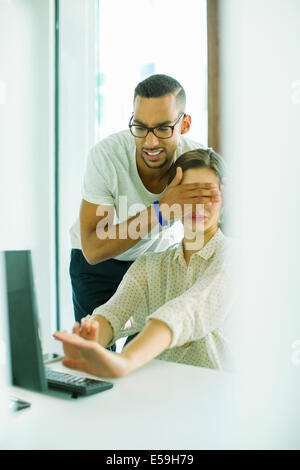 Uomo di copertura del collega agli occhi in ufficio Foto Stock