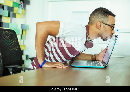 L'uomo kissing portatile in ufficio Foto Stock