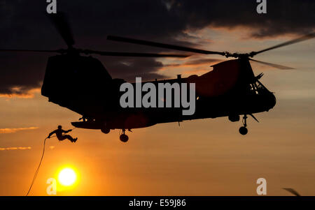 Un U.S. Marine Commando con il 4° Battaglione di ricognizione si stagliano da sole di setting come egli rappels al di fuori di un CH-46E MARE Foto Stock