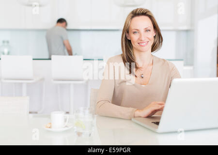 Donna che utilizza computer portatile al tavolo per la colazione Foto Stock