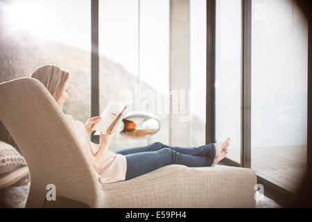 Donna lettura sul divano nel soggiorno moderno Foto Stock