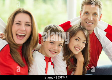 Famiglia nelle maglie dello sport il tifo nel soggiorno Foto Stock