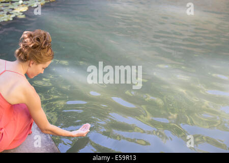 Donna immergendo la mano in piscina Foto Stock