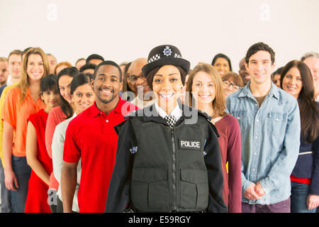 Ritratto di sorridere poliziotta nella parte anteriore del grande folla Foto Stock