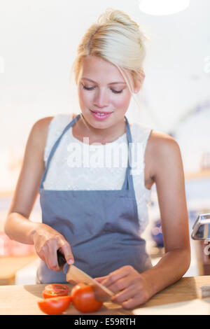 La donna per affettare verdura in cucina Foto Stock