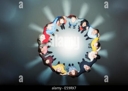 La gente di affari formando huddle intorno a una luce brillante Foto Stock