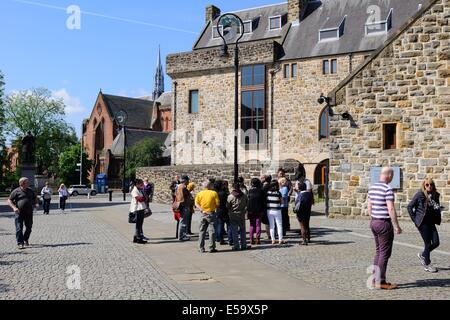 Una guida raduna il suo gruppo di turisti presso il Museo di arte religiosa e la vita a Glasgow, Scozia Foto Stock