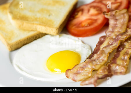 Una gustosa prima colazione Inglese con uova fritte, pancetta, toast e pomodori Close Up Foto Stock