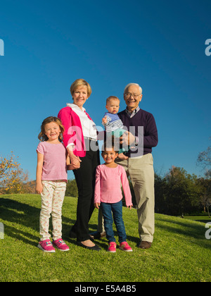 Coppia di anziani e nipoti sorridere insieme all'aperto Foto Stock