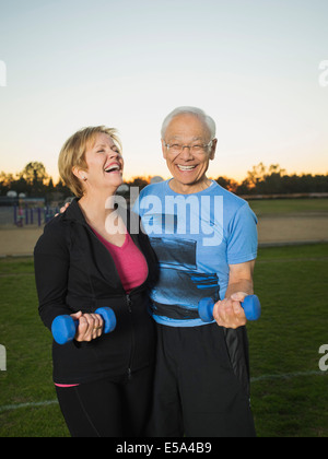 Coppia di anziani il sollevamento pesi insieme nel parco urbano Foto Stock