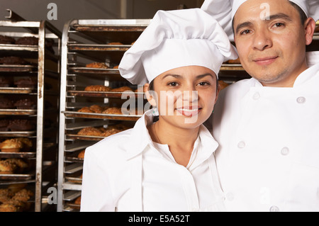 Ispanico bakers sorridente in forno Foto Stock