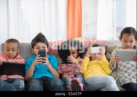 I bambini utilizzando la tecnologia sul divano Foto Stock