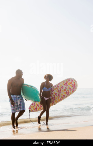 Giovane che trasportano le tavole da surf in spiaggia Foto Stock