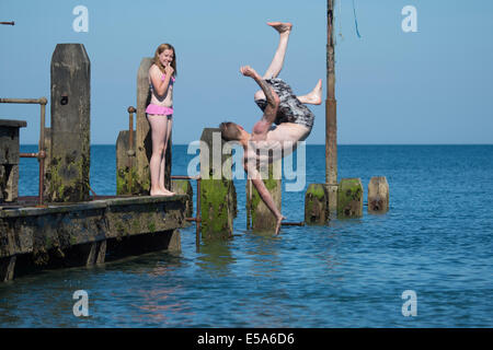 Aberystwyth, Wales UK, Venerdì 25 Luglio 2014 con temperature già a metà del 20s centigradi subito dopo 10am, la mattina presto nuotatori divertirsi salta fuori il pontile in legno sulla spiaggia a Aberystwyth sulla West Wales coast UK. Oggi la temperatura di picco è atteso a circa 25c, uno scambiatore di calore a pochi gradi rispetto a questi ultimi giorni ma ancora al di sopra della media per questo periodo dell'anno. Credito: keith morris/Alamy Live News Foto Stock