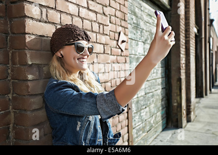 La donna sta immagine di se stessa su una strada di città Foto Stock