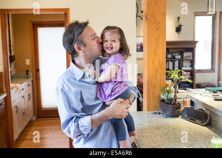 Padre baciare la figlia in cucina Foto Stock