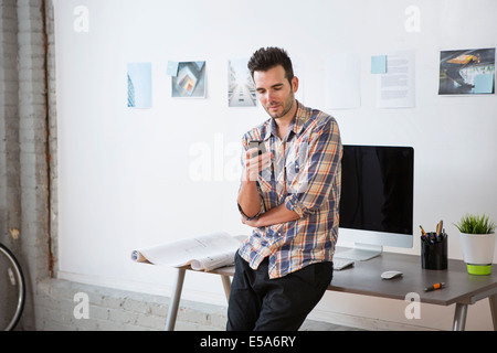 Architetto caucasica utilizzando il cellulare in ufficio Foto Stock