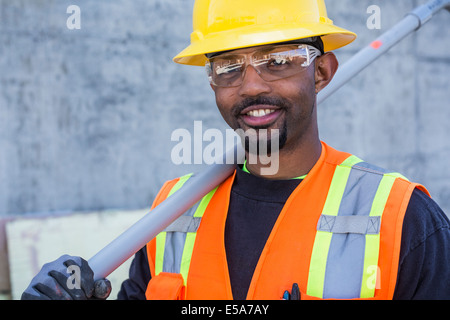 Lavoratore nero sorridente sul sito in costruzione Foto Stock