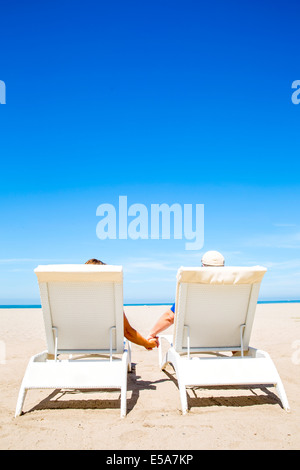 Giovane holding hands in sedie a sdraio sulla spiaggia Foto Stock