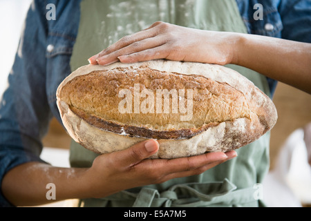 Razza mista donna holding pagnotta di pane Foto Stock