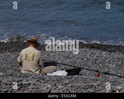 Uomo di mezza età la preparazione di canna da pesca sulla spiaggia, Millock, Bude, Cornwall, Regno Unito Foto Stock