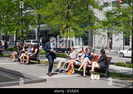 Gli impiegati per godersi il sole durante la pausa pranzo su Victoria Square, Montreal, provincia del Québec in Canada. Foto Stock