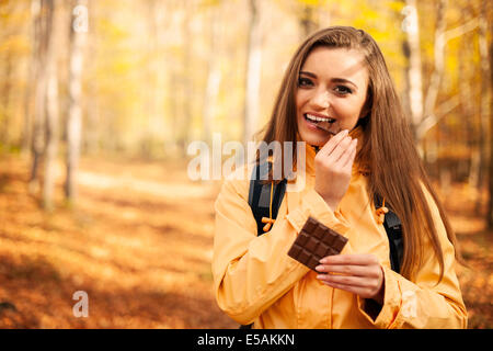 Felice giovane donna escursionista mangiando cioccolato, Debica, Polonia Foto Stock