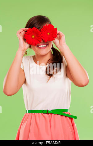 Donna sorridente che copre la sua gli occhi con due fiori, Debica, Polonia Foto Stock