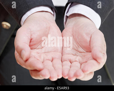 Vista frontale di imprenditore tenendo una manciata di vuoto da due palme- gesto a mano Foto Stock