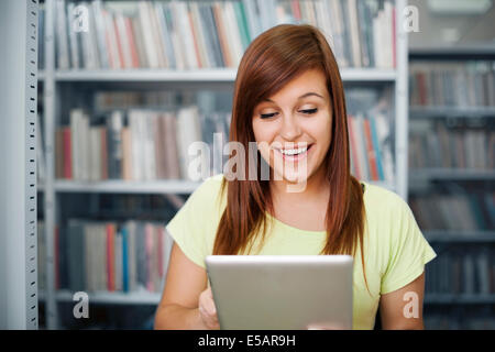 Felice studente utilizzando digitale compressa nella libreria Debica, Polonia Foto Stock