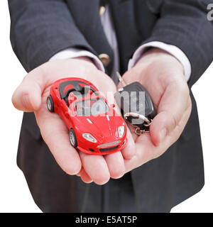 Auto rossa e la chiave nel venditore la mano isolati su sfondo bianco Foto Stock