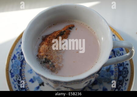 Blue tazza di porcellana sul piattino con latte caldo dolce al cioccolato e piccolo pezzo di golden toast in Foto Stock