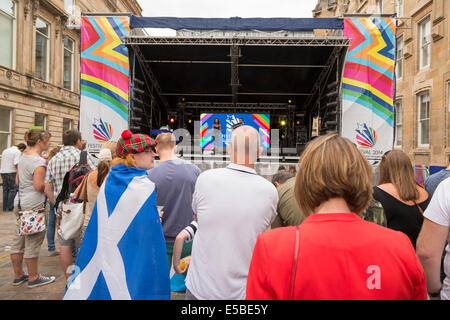 Ragazzo con bandiera scozzese drappeggiati oltre le sue spalle orologi una performance sul palco a Glasgow, Scotland, Regno Unito 2014 Foto Stock