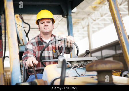 Lavoratore pilotaggio di pesanti attrezzature da costruzione - bulldozer o il retroescavatore. Foto Stock