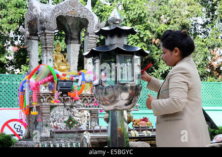 Bangkok in Thailandia - illuminazione donna incenso stick per la buona fortuna presso un santuario buddista Foto Stock