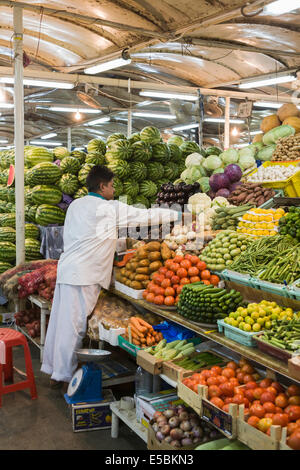 Stile di vita: maschio locale organizza stallholder produrre su una bancarella vendendo coloratissimi banchi di frutta e verdura al mercato del pesce souk, Deira, Dubai Foto Stock