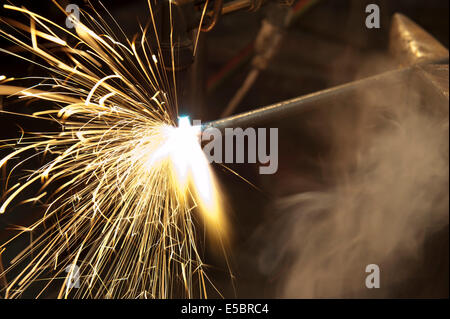 Un costruttore di metallo utilizzando una torcia a calore di un pezzo di metallo per dare forma a. Foto Stock