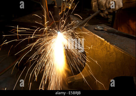 Un costruttore di metallo utilizzando una torcia a calore di un pezzo di metallo per dare forma a. Foto Stock