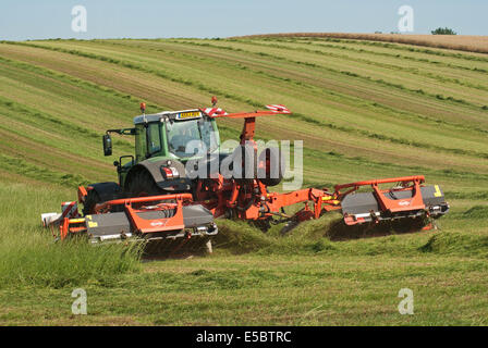 Trattore tirando l'erba-cutter taglio di erba per la produzione di fieno Foto Stock