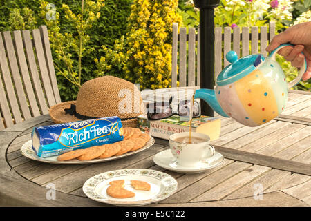 Il tè che viene versato di avere con ricchi Biscotti da tè in giardino (2 di 2) Foto Stock