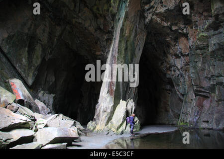 Solitaria figura femminile in piedi in un uomo fatto di caverna conosciuta come Cattedrale cava in Little Langdale nel Lake District inglese Foto Stock