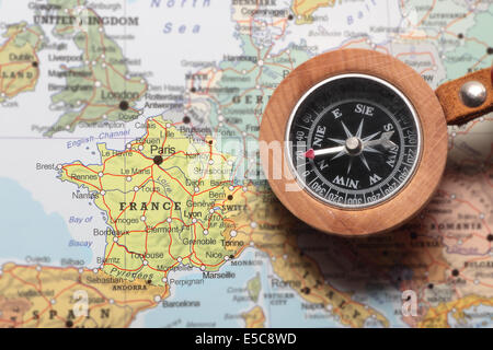 Bussola su una mappa puntando verso la Francia e la pianificazione di una destinazione di viaggio Foto Stock