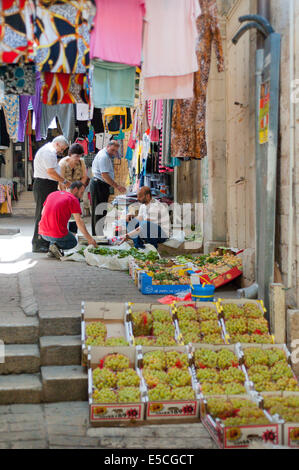 Una frutta & verdura fornitore e gli acquirenti scelgono di uve fresche foglie presso il mercato nella città vecchia di Nazareth, Israele Foto Stock