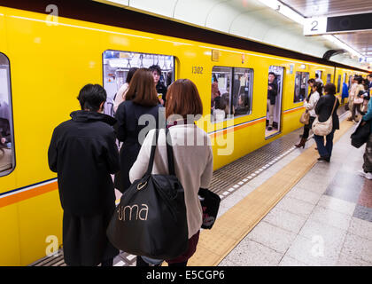 La gente a una stazione della metropolitana platform immettendo un treno. Tokyo Metro, Tokyo, Giappone. Foto Stock