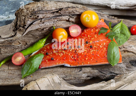 Vista orizzontale di materie filetto di salmone, lato di pelle verso il basso con il condimento all'interno del legno di deriva Foto Stock