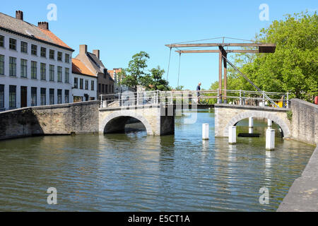 Biker attraversa un ponte levatoio in legno sul canale della città vecchia di Bruges, Belgio Foto Stock