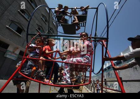 La città di Gaza, Striscia di Gaza, Territori palestinesi. 28 Luglio, 2014. Bambini palestinesi giocare su un mini ruota panoramica Ferris al di fuori di una organizzazione delle Nazioni Unite (ONU) School di Jabalia nel nord della striscia di Gaza, il 28 luglio 2014, sull'inizio della festività musulmana di Eid termina il mese di digiuno del Ramadan. Serbatoio israeliano fuoco uccise un quattro-anno-vecchio ragazzo nel nord della Striscia di Gaza, la prima morte poiché i due lati ha cominciato a osservare una tregua non ufficiale, medics palestinese detto credito: Ashraf Amra/immagini APA/ZUMA filo/Alamy Live News Foto Stock