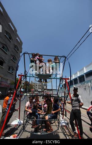 La città di Gaza, Striscia di Gaza, Territori palestinesi. 28 Luglio, 2014. Bambini palestinesi giocare su un mini ruota panoramica Ferris al di fuori di una organizzazione delle Nazioni Unite (ONU) School di Jabalia nel nord della striscia di Gaza, il 28 luglio 2014, sull'inizio della festività musulmana di Eid termina il mese di digiuno del Ramadan. Serbatoio israeliano fuoco uccise un quattro-anno-vecchio ragazzo nel nord della Striscia di Gaza, la prima morte poiché i due lati ha cominciato a osservare una tregua non ufficiale, medics palestinese detto credito: Ashraf Amra/immagini APA/ZUMA filo/Alamy Live News Foto Stock