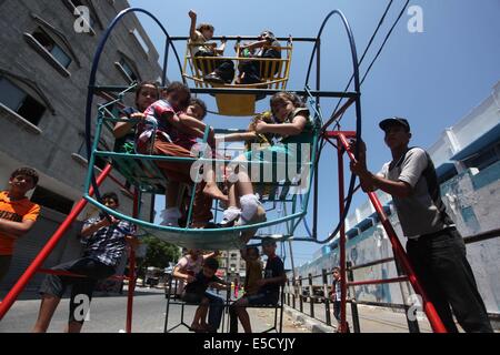 La città di Gaza, Striscia di Gaza, Territori palestinesi. 28 Luglio, 2014. Bambini palestinesi giocare su un mini ruota panoramica Ferris al di fuori di una organizzazione delle Nazioni Unite (ONU) School di Jabalia nel nord della striscia di Gaza, il 28 luglio 2014, sull'inizio della festività musulmana di Eid termina il mese di digiuno del Ramadan. Serbatoio israeliano fuoco uccise un quattro-anno-vecchio ragazzo nel nord della Striscia di Gaza, la prima morte poiché i due lati ha cominciato a osservare una tregua non ufficiale, medics palestinese detto credito: Ashraf Amra/immagini APA/ZUMA filo/Alamy Live News Foto Stock