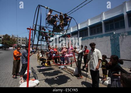 La città di Gaza, Striscia di Gaza, Territori palestinesi. 28 Luglio, 2014. Bambini palestinesi giocare su un mini ruota panoramica Ferris al di fuori di una organizzazione delle Nazioni Unite (ONU) School di Jabalia nel nord della striscia di Gaza, il 28 luglio 2014, sull'inizio della festività musulmana di Eid termina il mese di digiuno del Ramadan. Serbatoio israeliano fuoco uccise un quattro-anno-vecchio ragazzo nel nord della Striscia di Gaza, la prima morte poiché i due lati ha cominciato a osservare una tregua non ufficiale, medics palestinese detto credito: Ashraf Amra/immagini APA/ZUMA filo/Alamy Live News Foto Stock